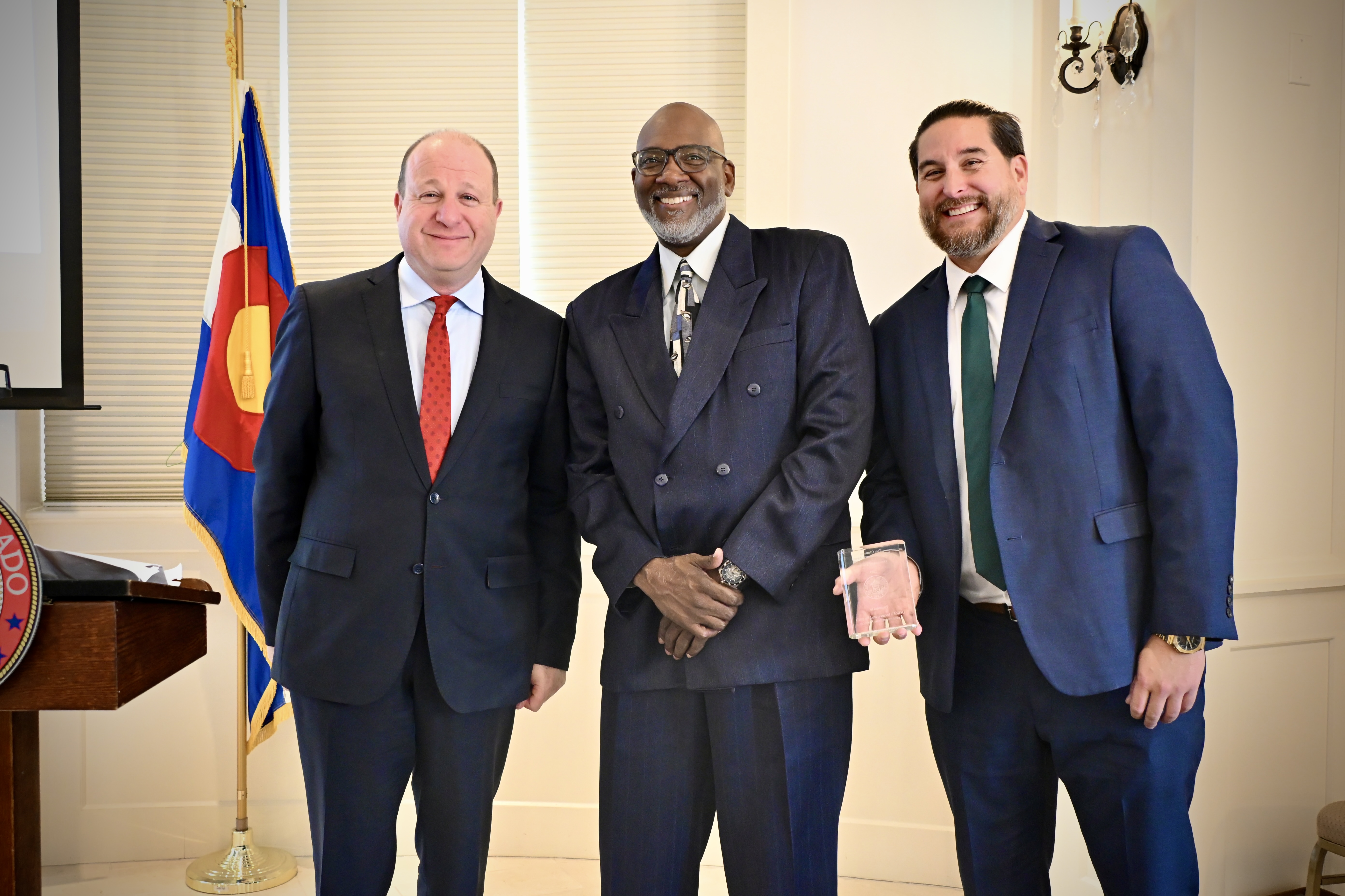 Pictured is Governor Polis, Clarence Wallace, and Royal Cameron